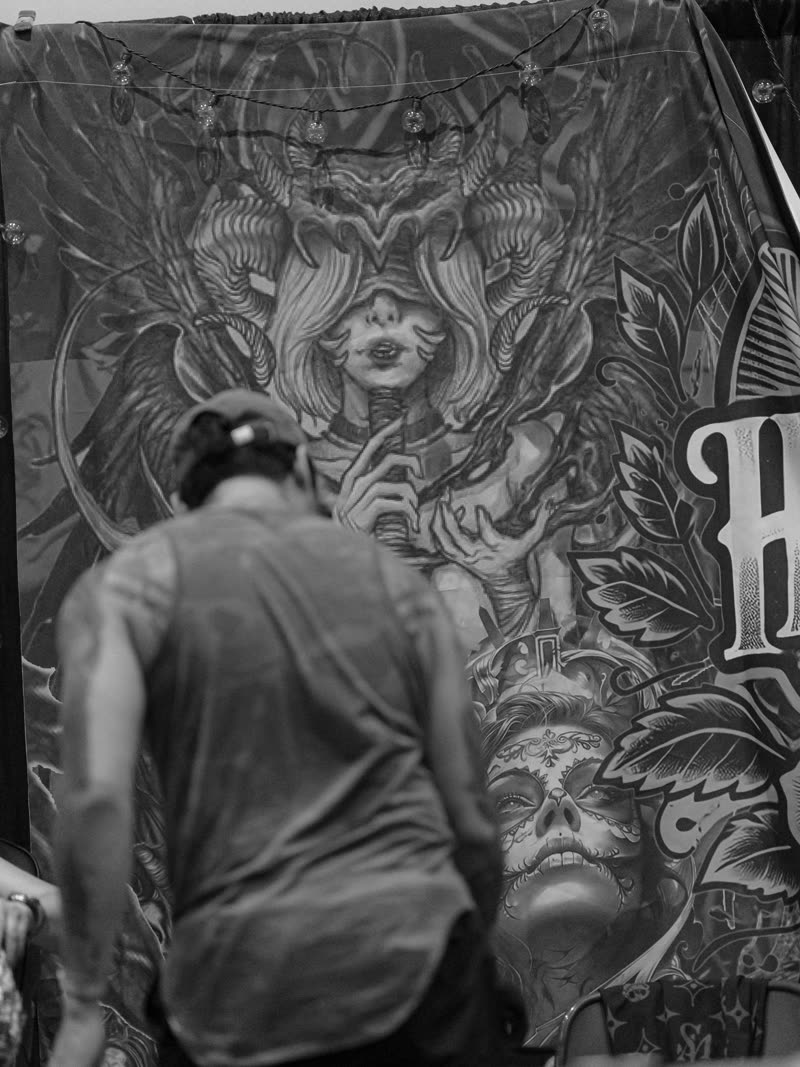 Artist seated against a full-wall illustrated banner, black and white
